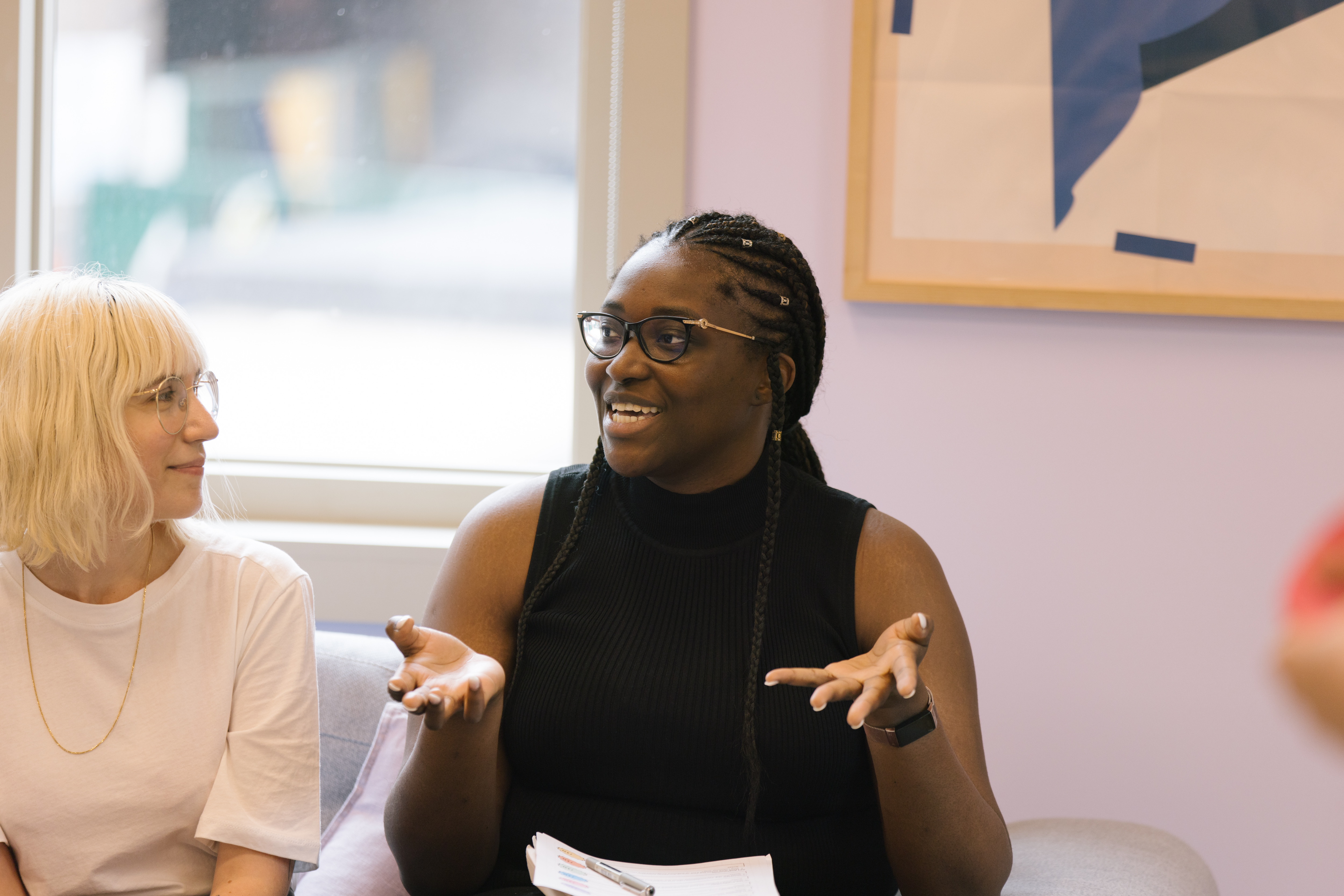 A woman is sat on a sofa presenting an idea to another woman sat next to her