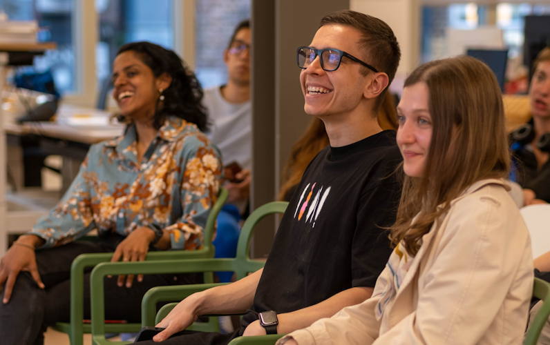 3 people smiling in a seated audience