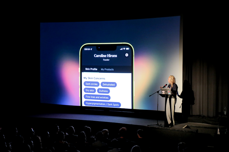 Caroline Hirons presents the Skin Rocks app on a large screen to an audience in a darkened theater.