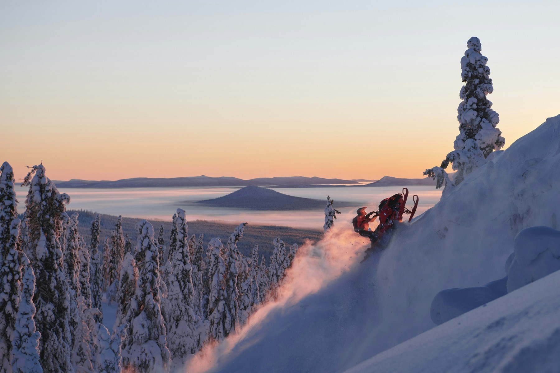 A snowmobile being driven in the sunset