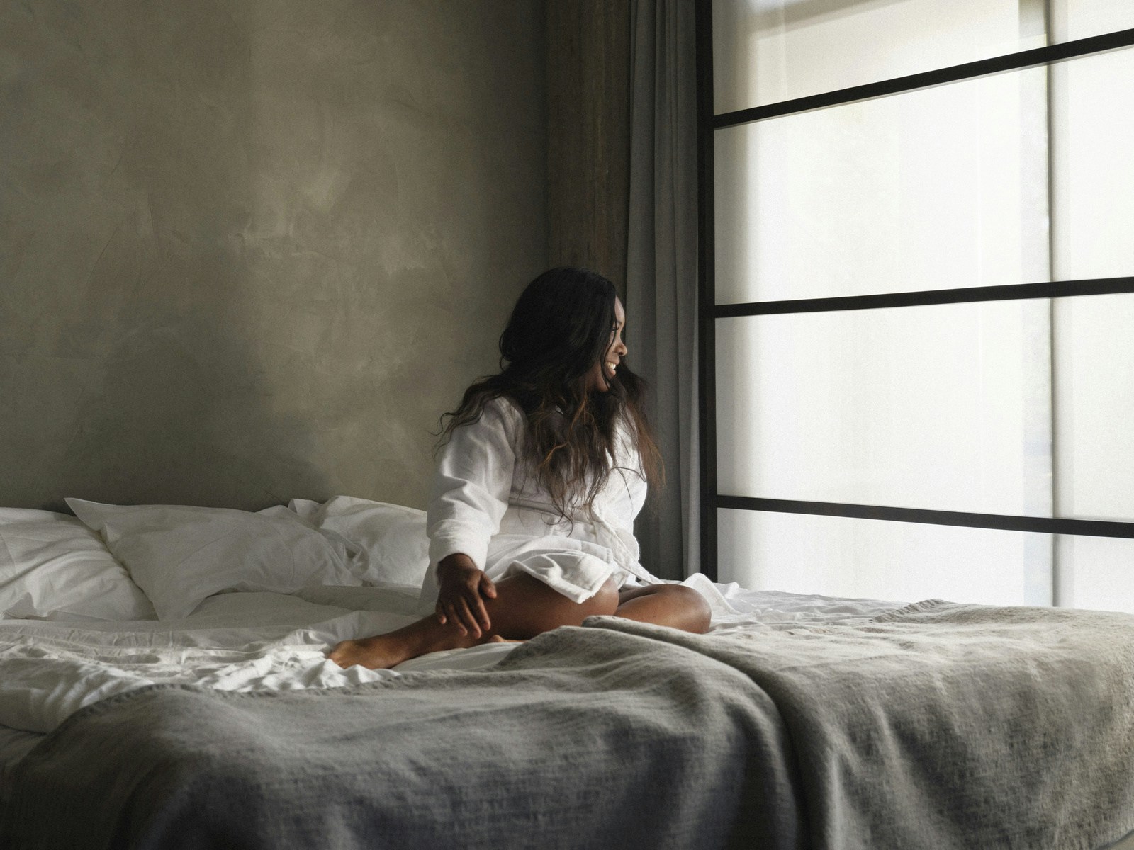 A woman sitting on a bed looking out the window