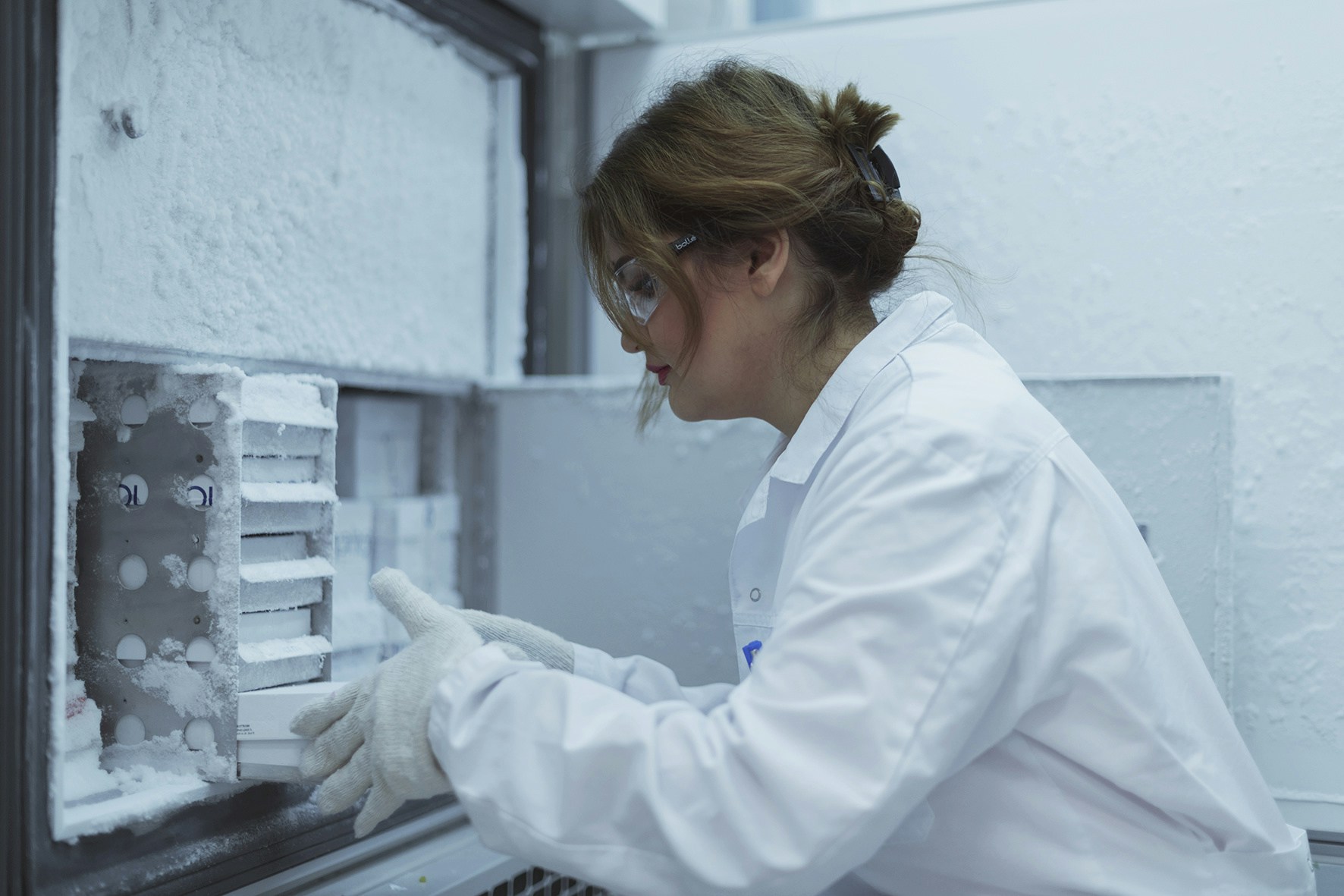 A scientist in a lab taking out samples out of a freezer