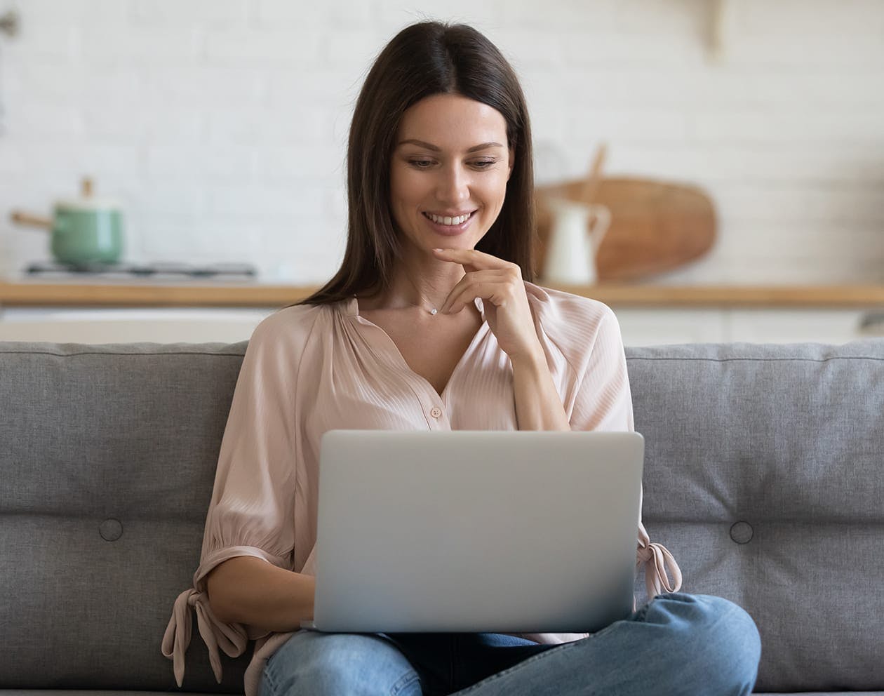woman sitting on the couch smiling with her laptop