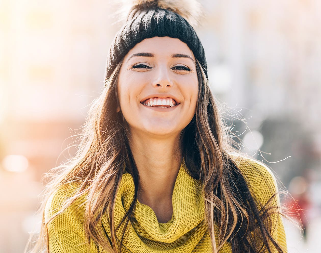 brunette woman wearing a black beanie and yellow sweater