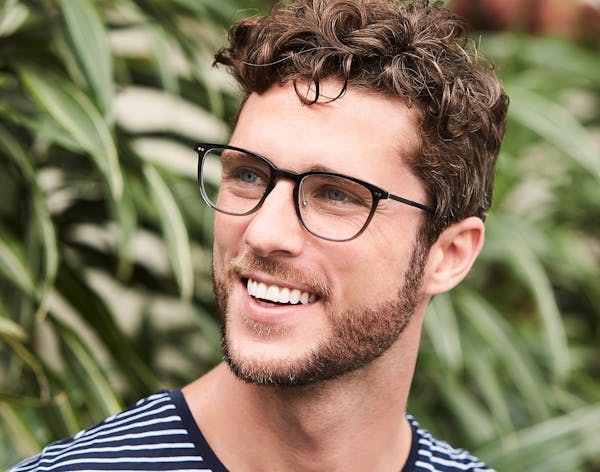 man with short brown curly hair wearing glasses