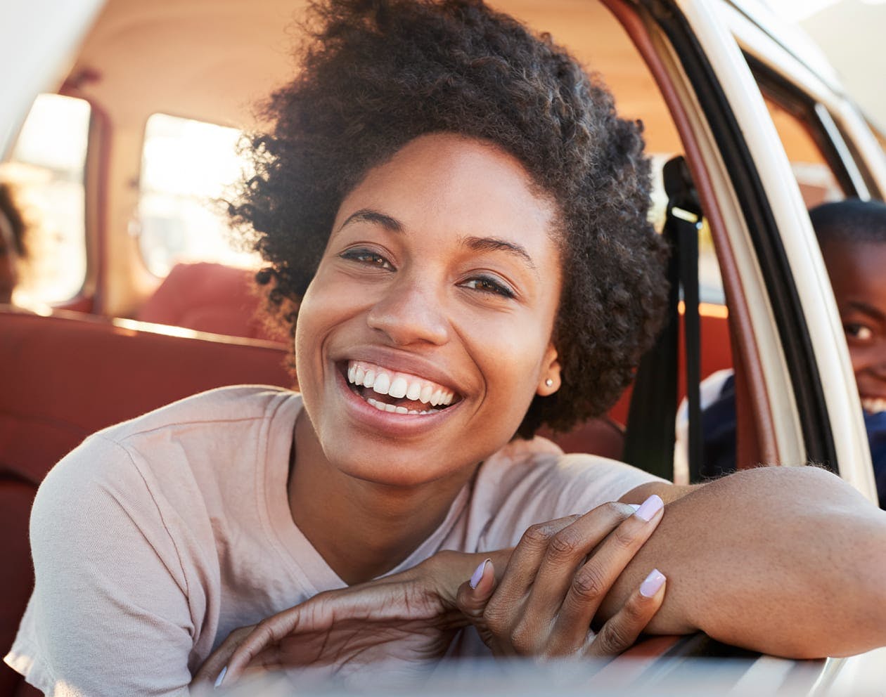woman riding in a car smiling with her arm out of the window