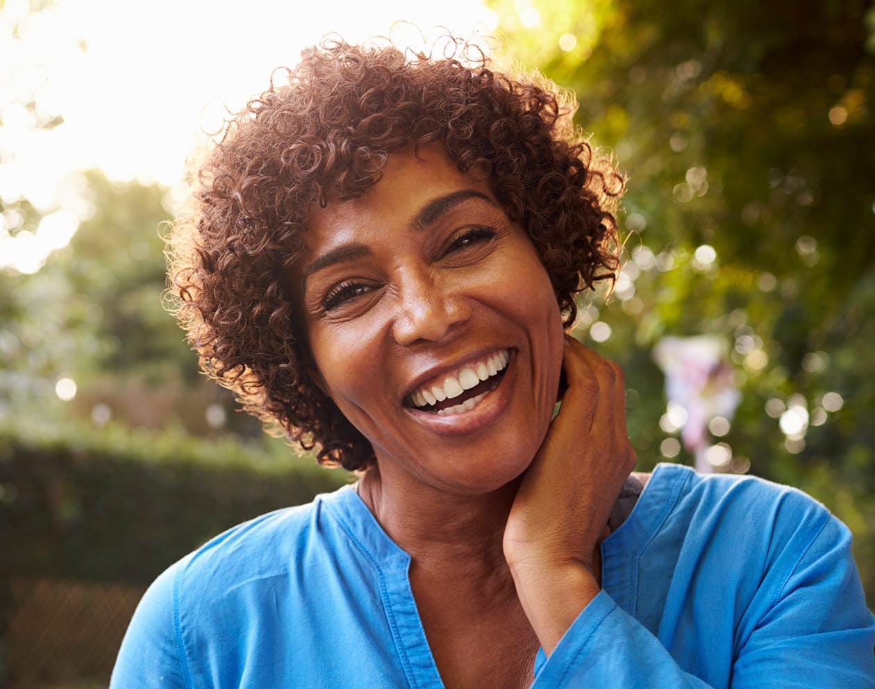 a woman with short brown curly hair in a bright blue top
