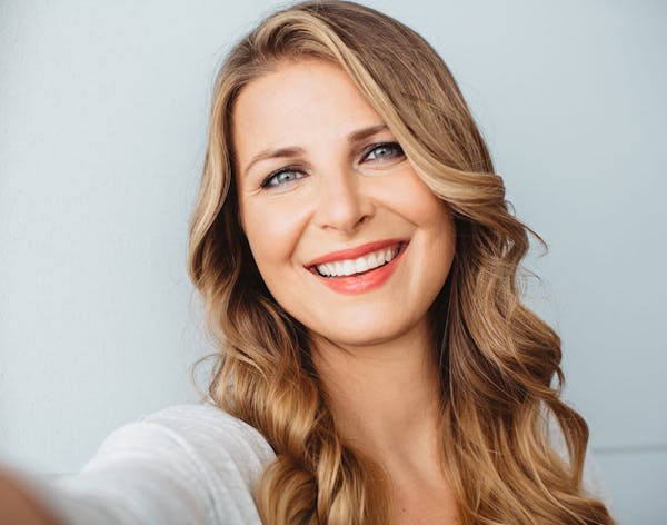 a blonde woman smiling in a white tshirt