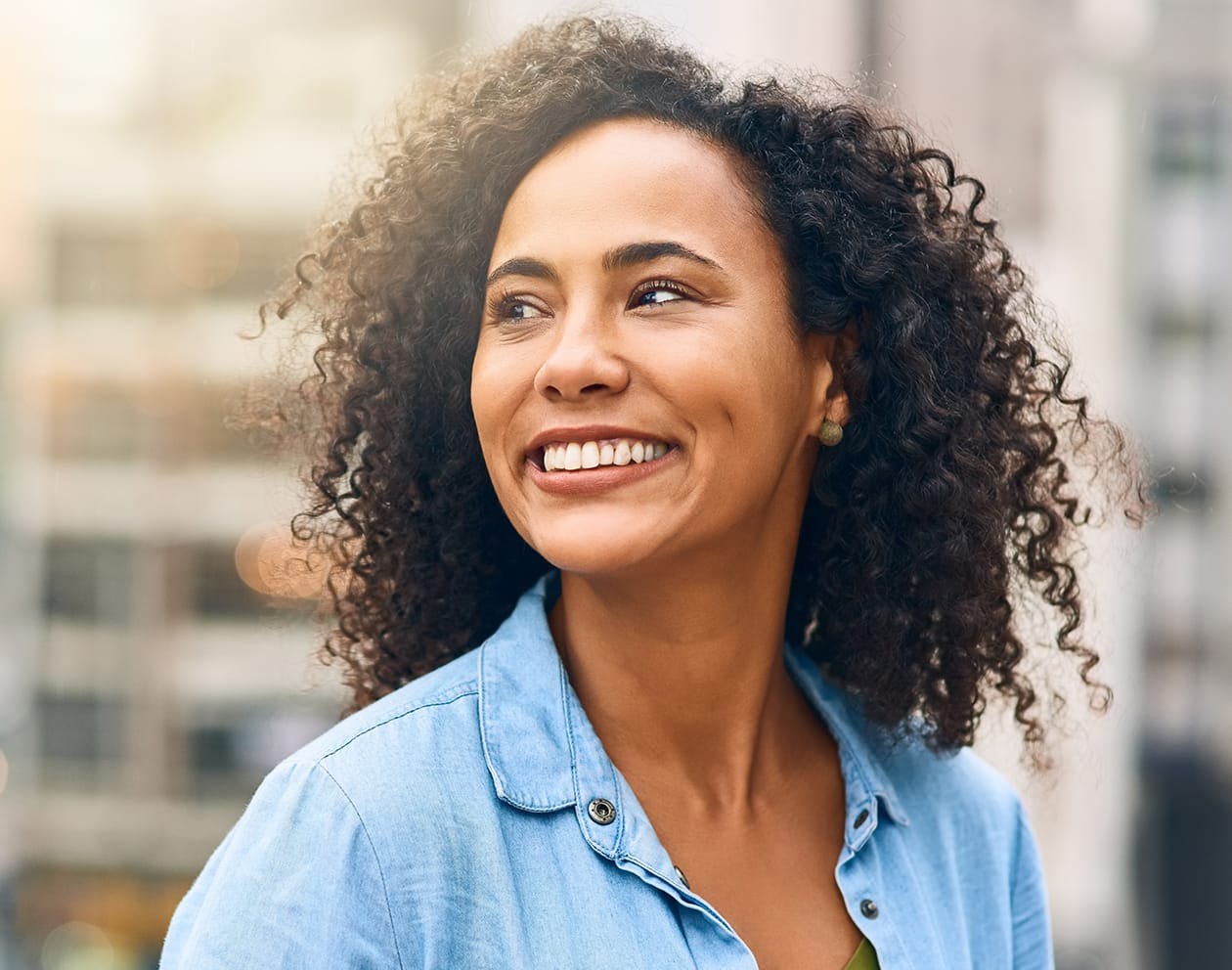 a woman with dark curly hair smiling in a blue top