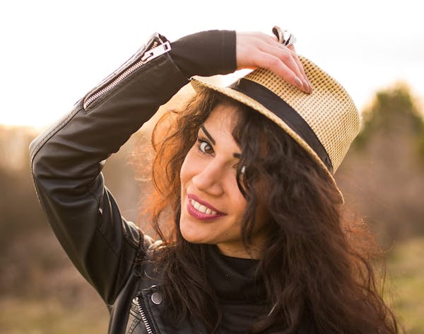 a woman with dark curly hair in a straw hat