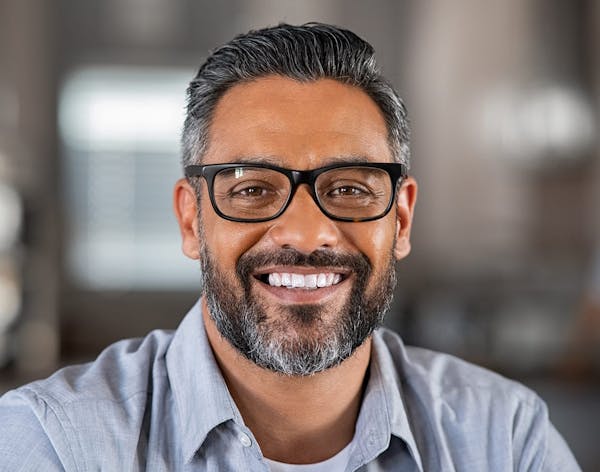 a man smiling with black eyeglasses
