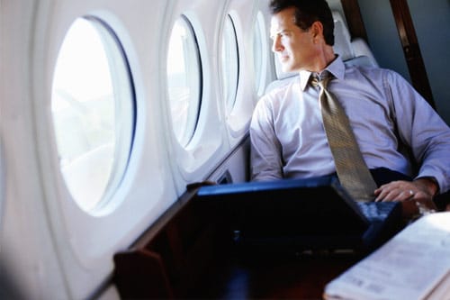 Business man sitting in plane, looking out window