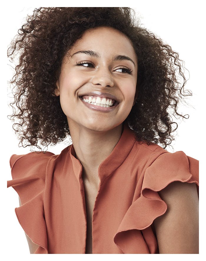 a woman with dark curly hair smiling really big