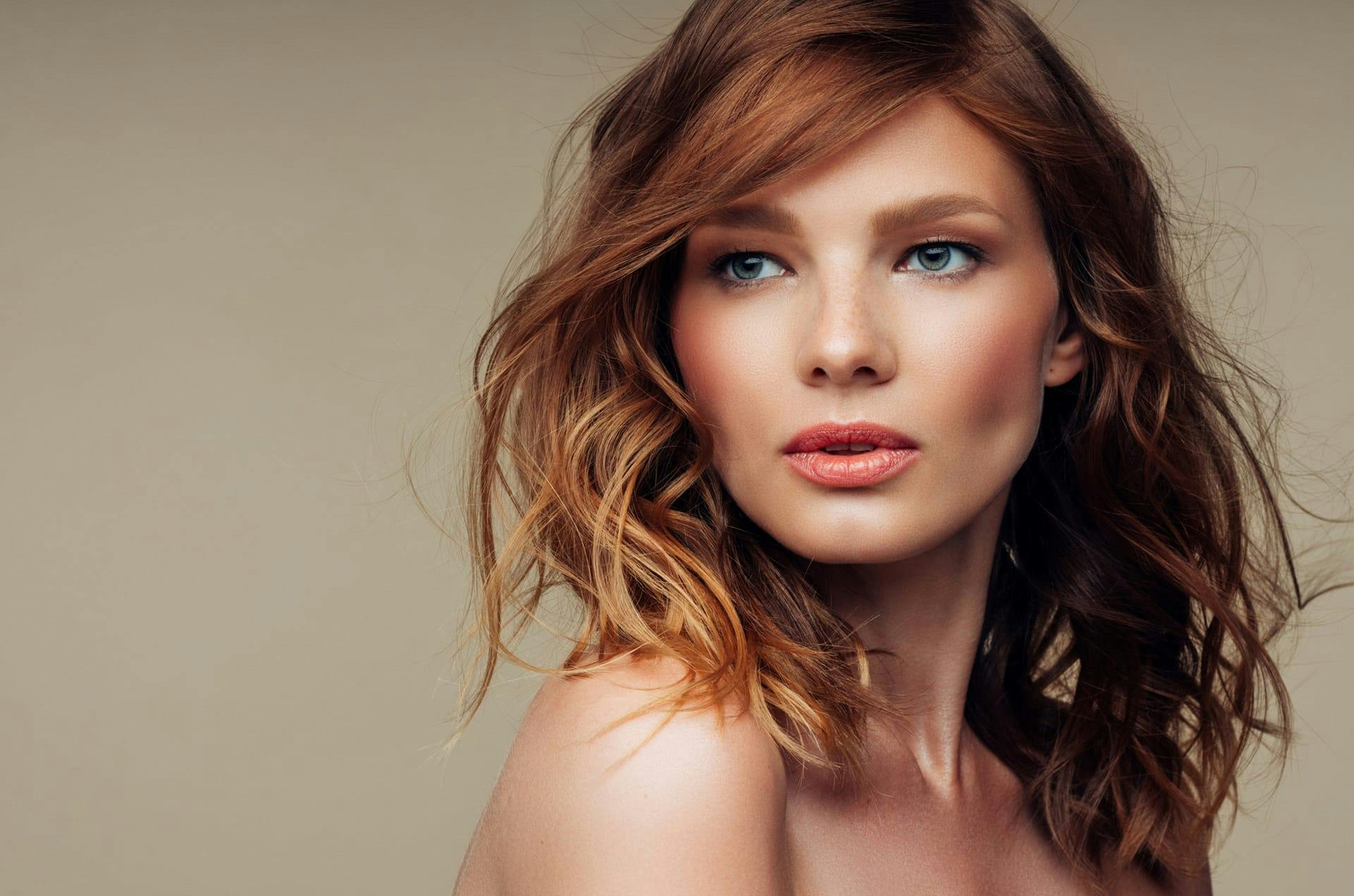 Woman with wavy red hair looking over her shoulder