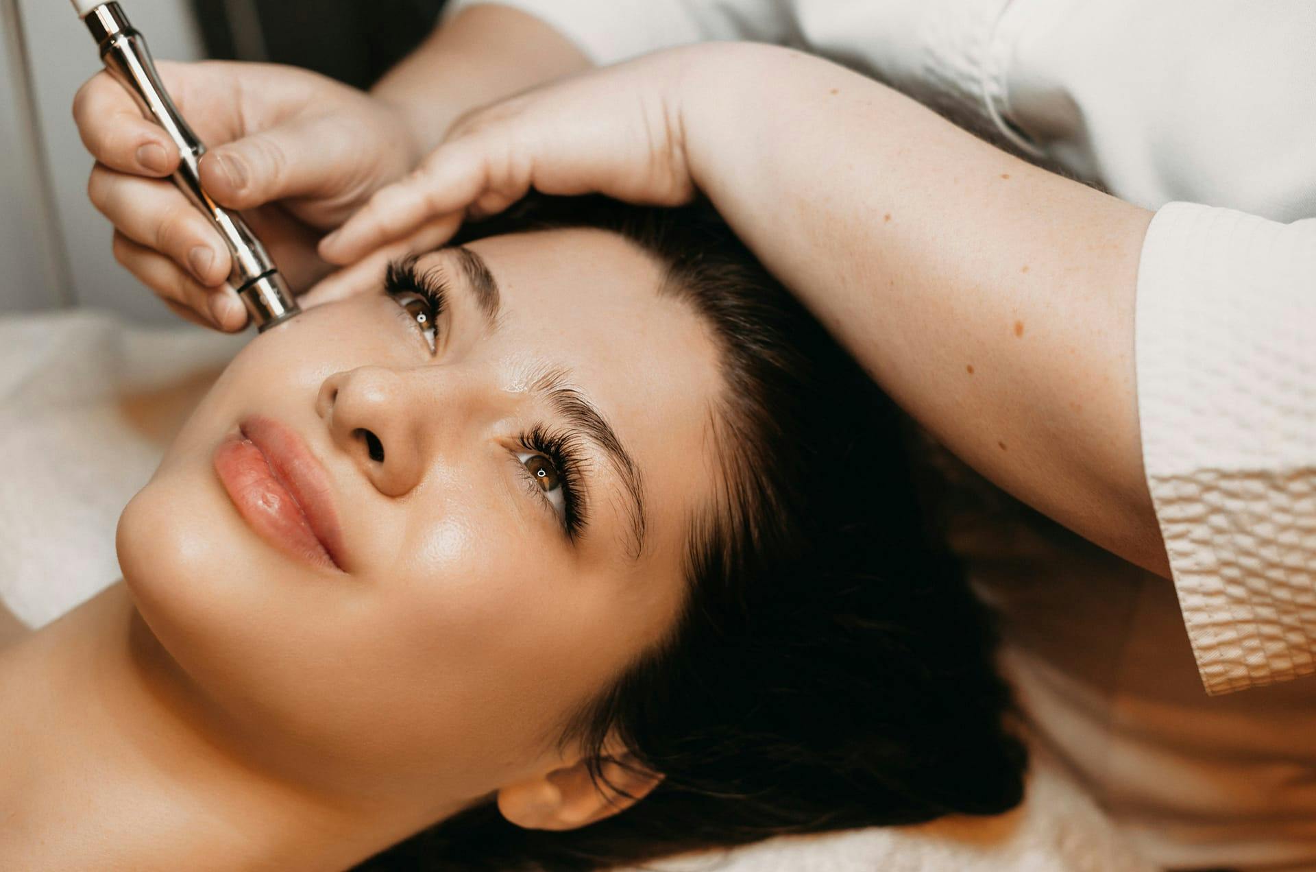 Woman getting microneedling treatment while lying down