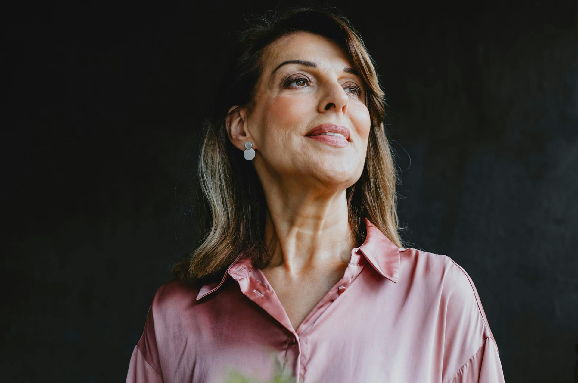 Woman in a button-down shirt looking to the side and smiling