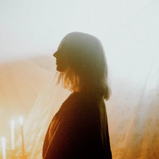 Profile view of Tiffany Hudson standing in front of lit candles