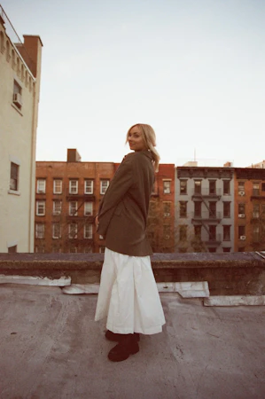 Tiffany on a rooftop, wearing a jacket over a white dress.