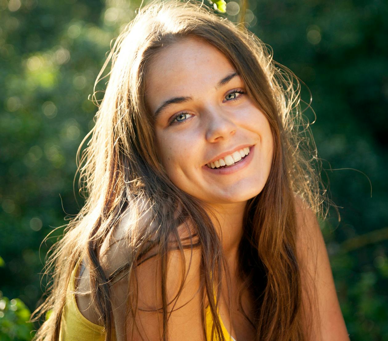 Young brown-haired girl smiling outside