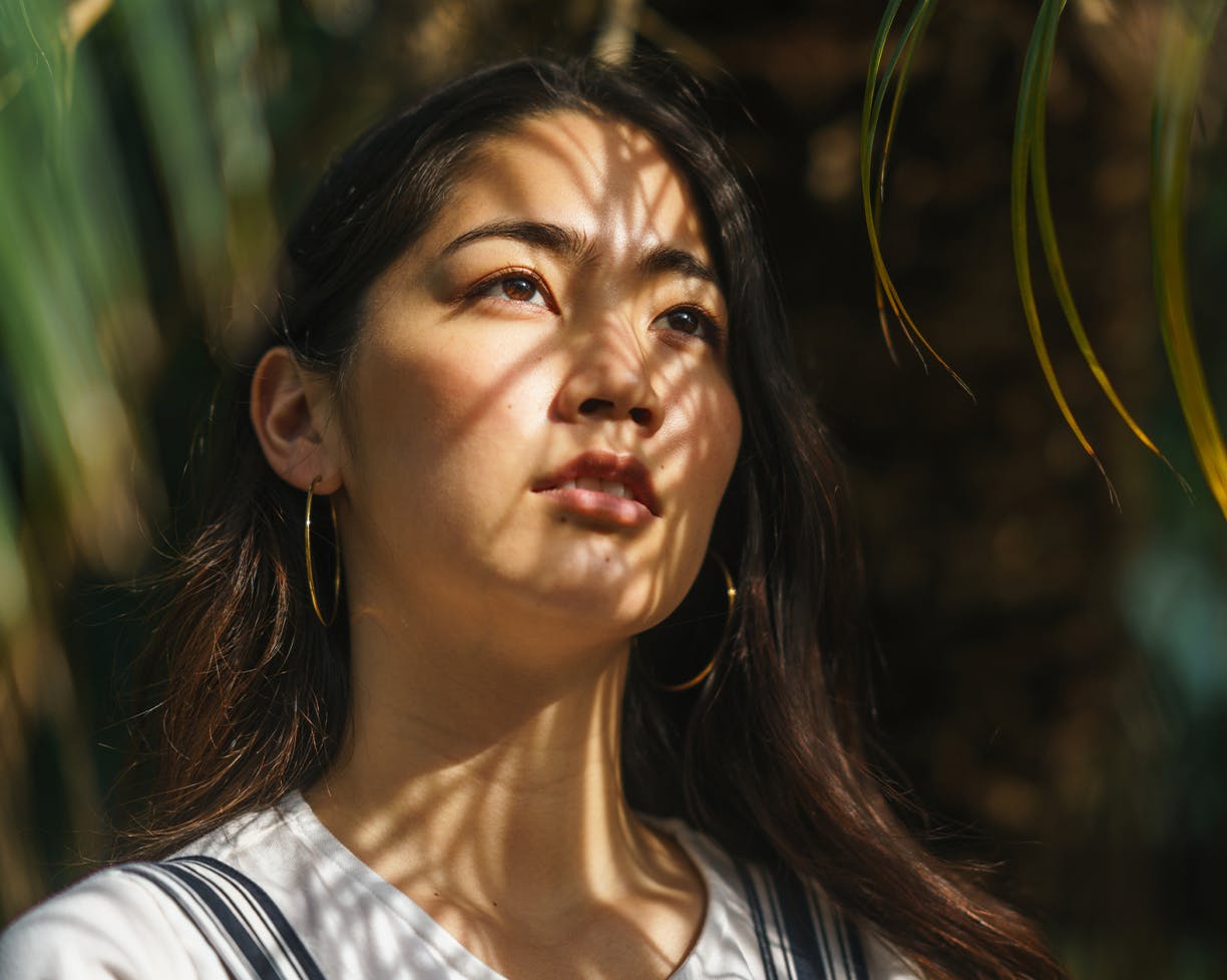 Asian woman posing under green plants