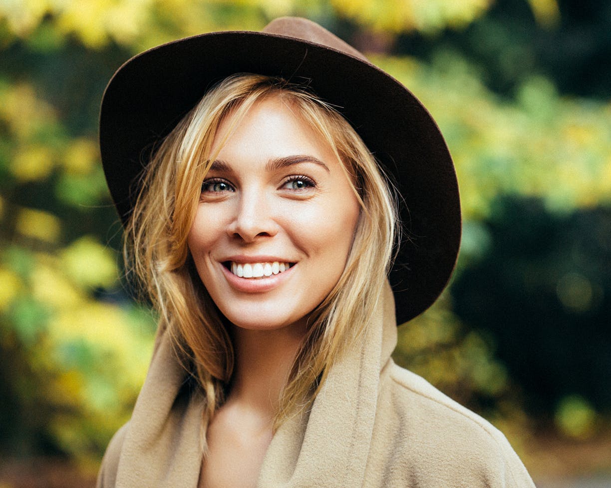 Blonde-haired woman wearing brown hat and smiling