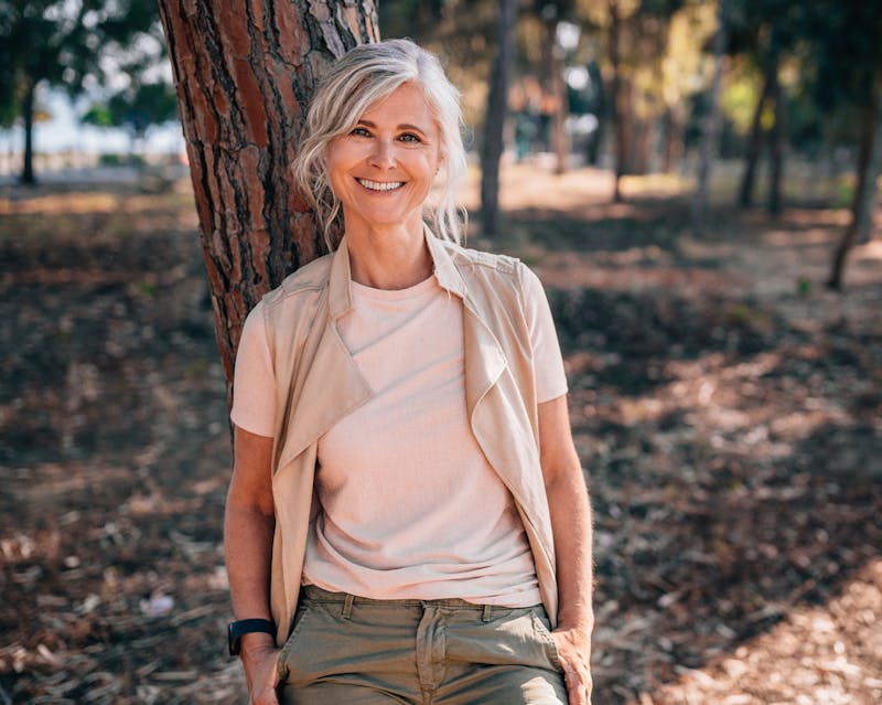 Middle-aged woman leaning against a tree
