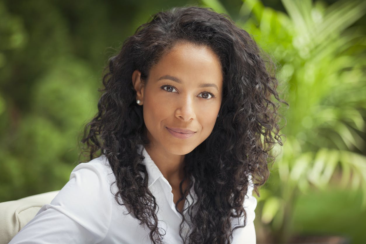 Woman with black, curly hair in a white shirt