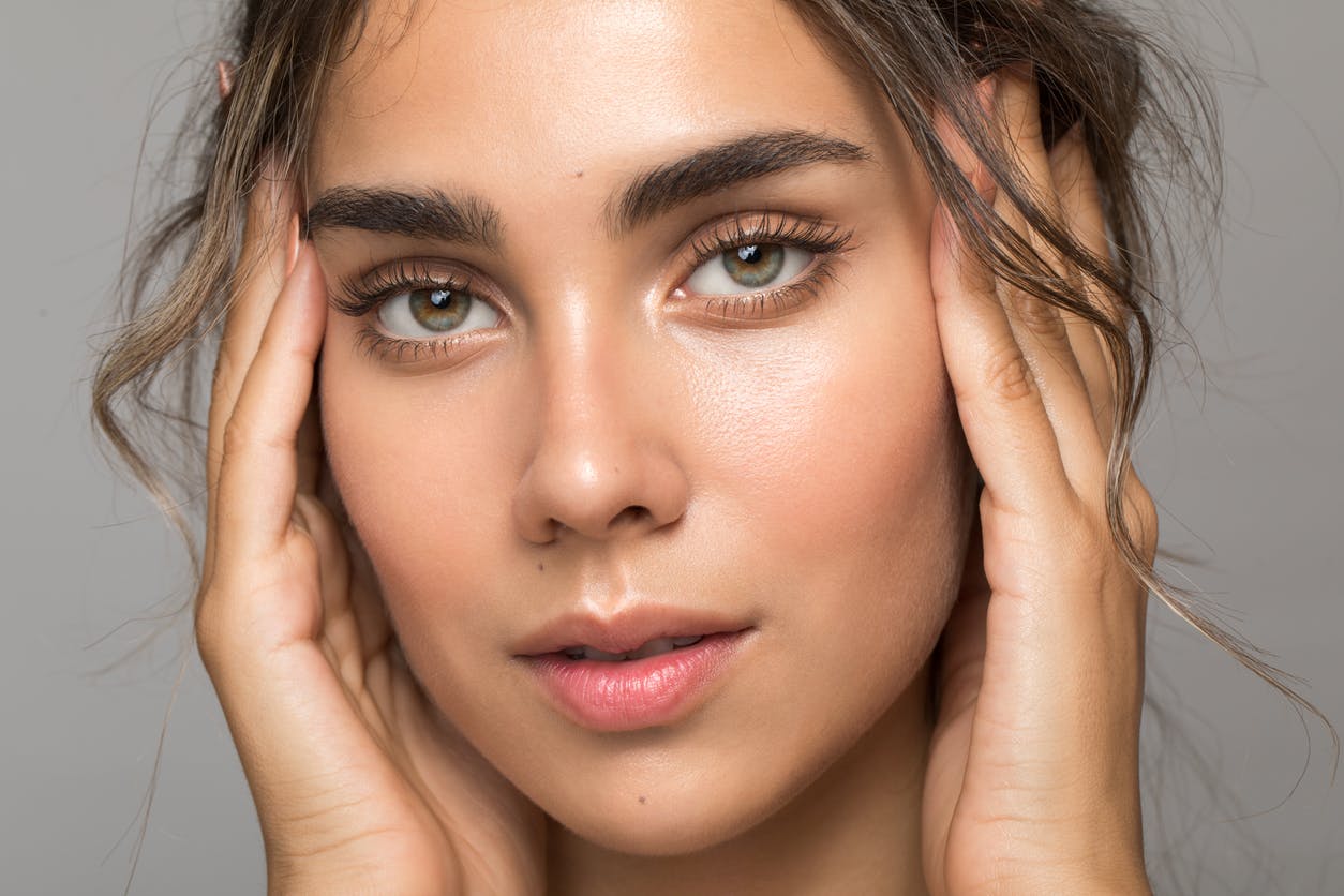 model with hands touching the side of her face