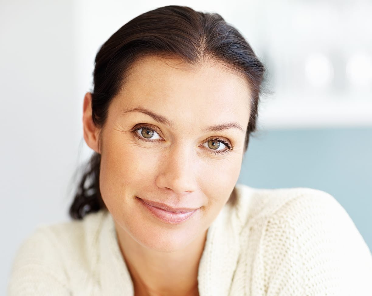 brunette model in light makeup in a white knit sweater