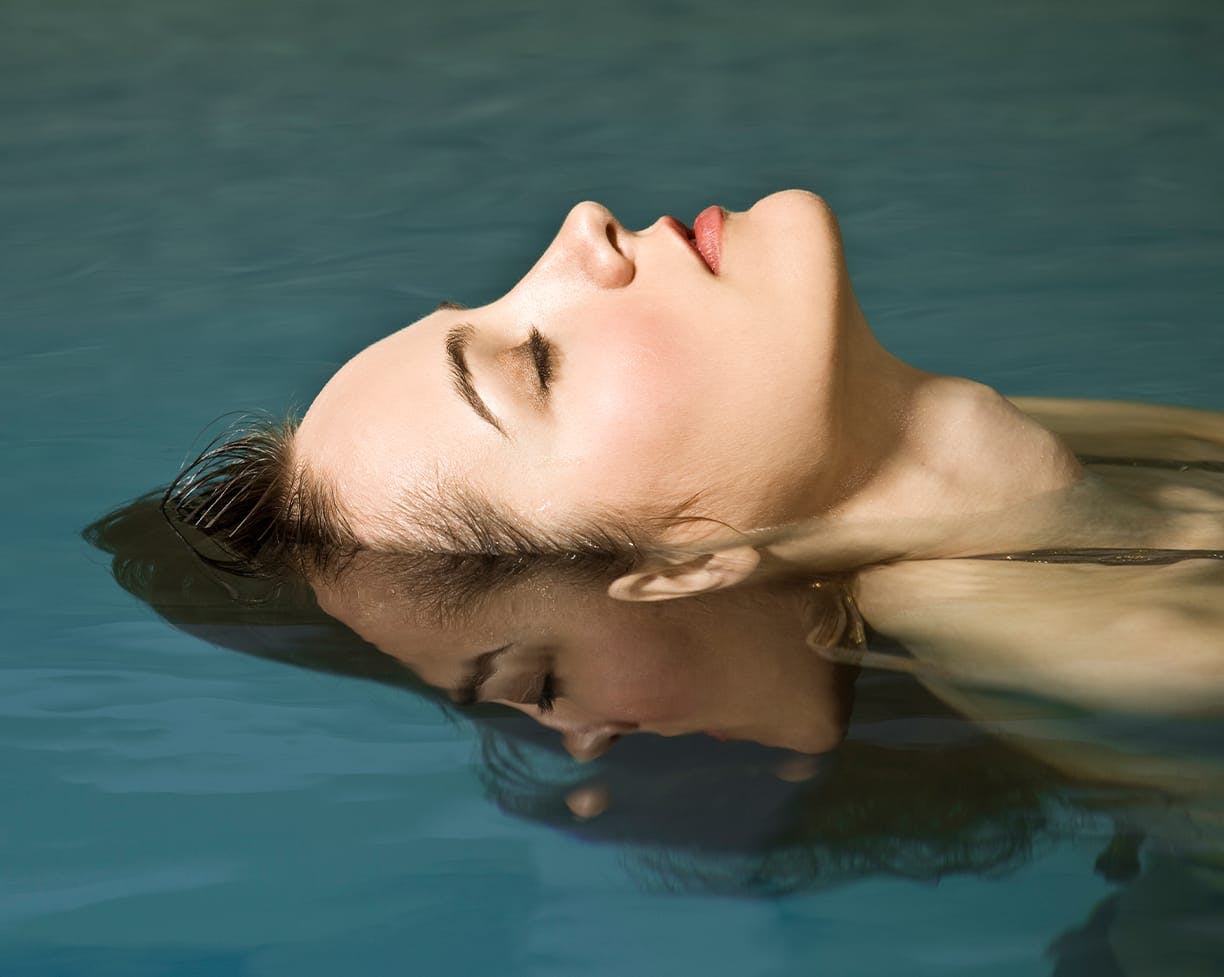 a brunette woman laying back in a pool