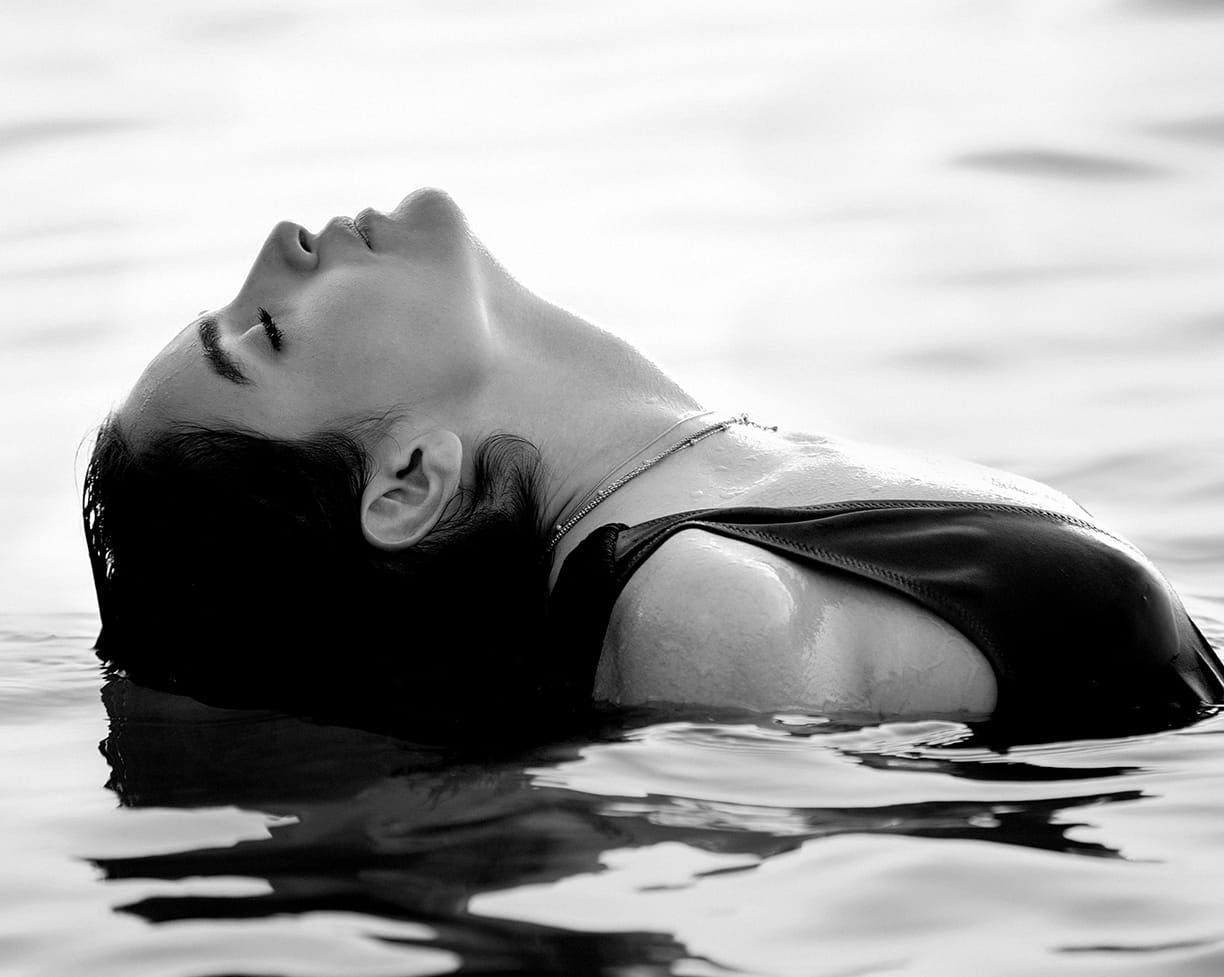 black and white image of a woman dipping her head in water