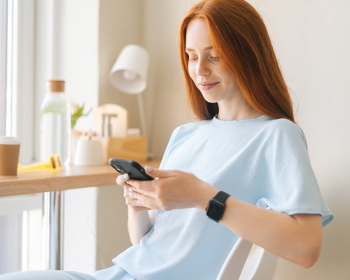 a redheaded woman smiling at her phone