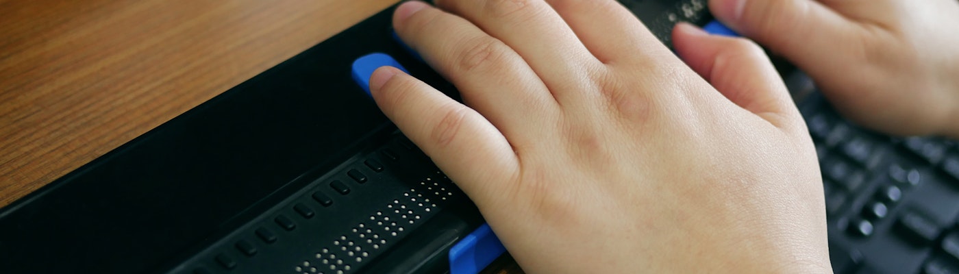Close-up van twee handen die gebruik maken van een computer met braille display of braille toetsenbord