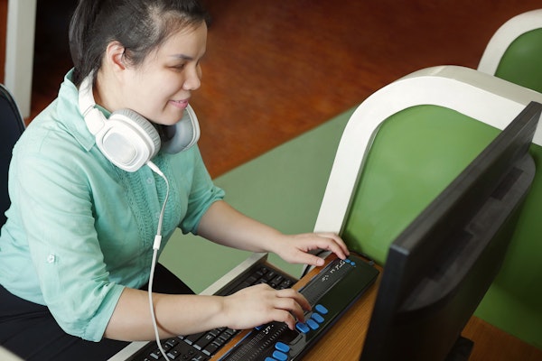 Vrouw leest met brailleregel van een computer beeldscherm