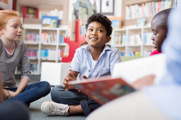 decoratief: kinderen die in een groepje lezen voor boekenkasten