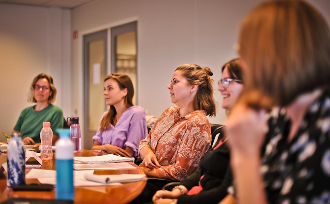 vijf mensen aan een tafel tijdens een workshop