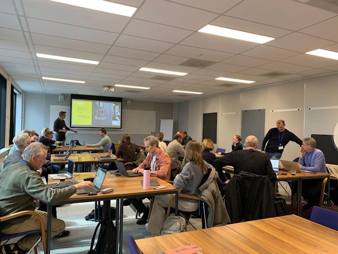 Mensen in een zaal gepositioneerd aan verschillende vierkante tafels