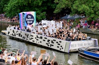 Boekenboot op het water met langs de kades juichende mensen