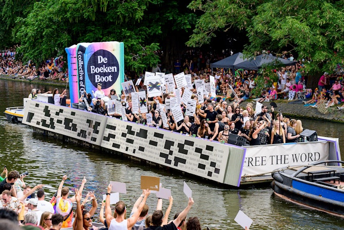 Boekenboot op het water met langs de kades juichende mensen