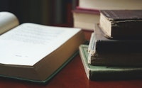 Links: opengeslagen boek. Rechts: twee stapeltjes boeken