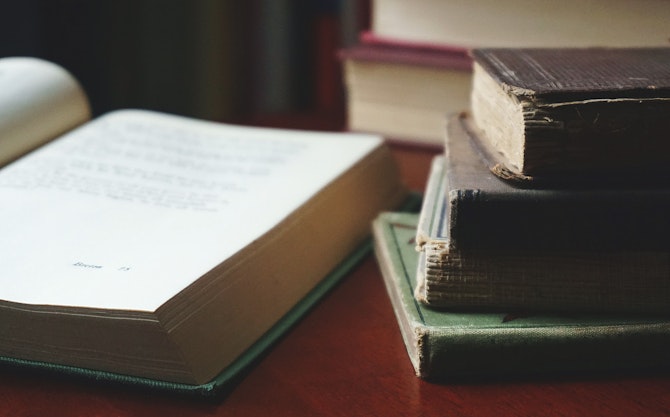 Links: opengeslagen boek. Rechts: twee stapeltjes boeken