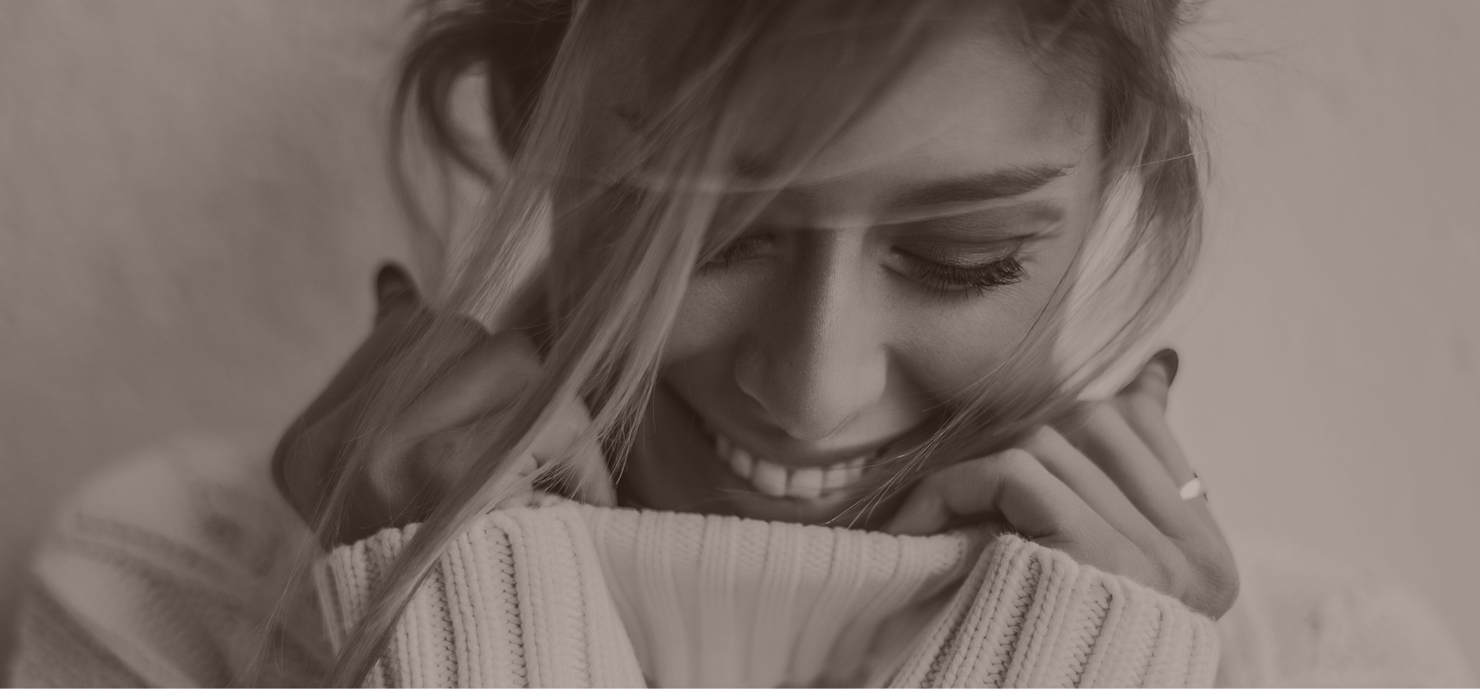 Black and white pic of a woman in a sweater laughing
