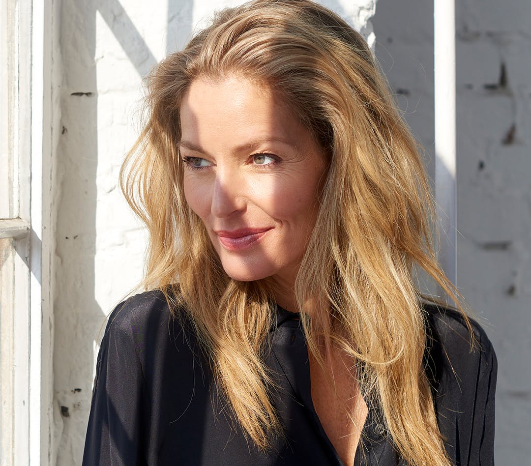 Older blonde woman in black looking out a window
