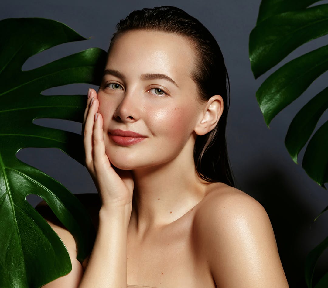 Woman in between leaves touching her face