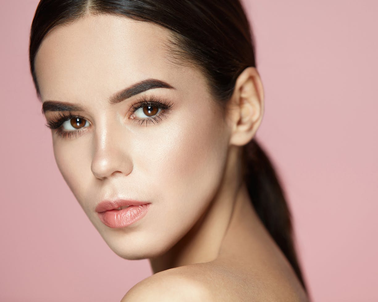 Brunette woman in front of a pink background
