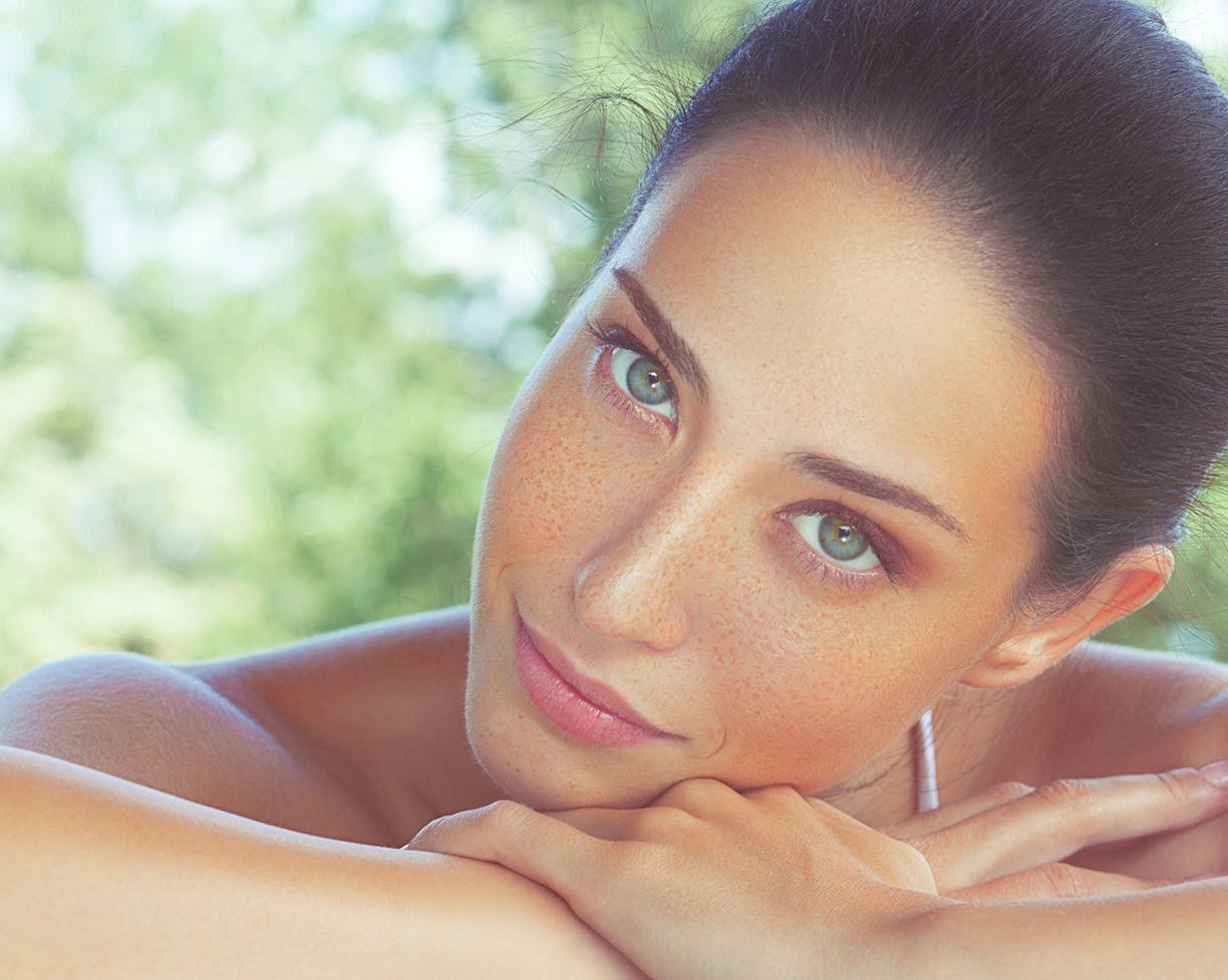 Woman with freckles laying her head on her arm