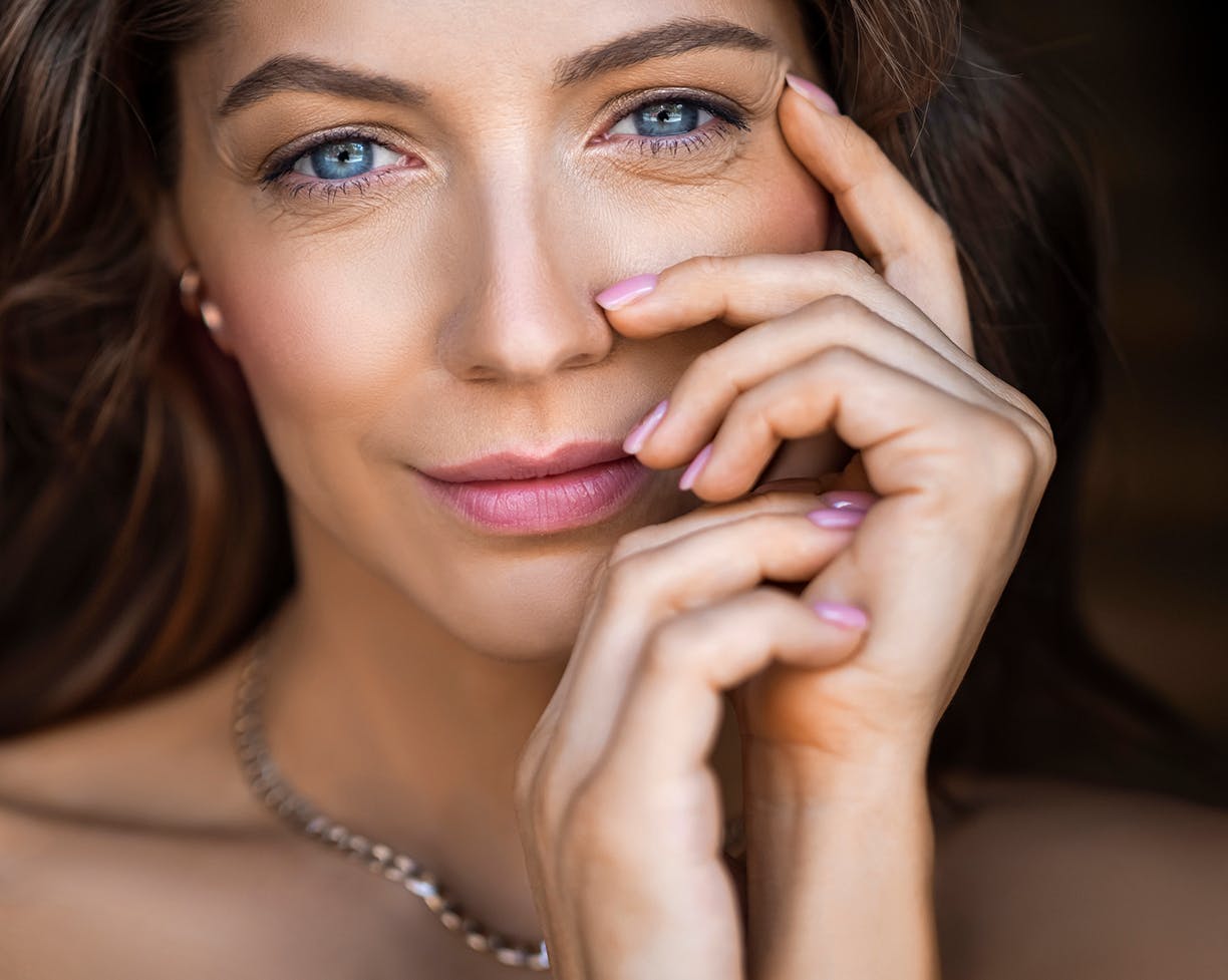 Brown-haired woman touching her face with her hand