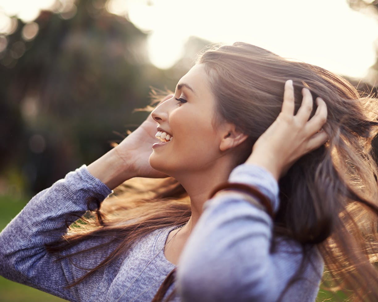 Dark-haired woman playing with her hair outside