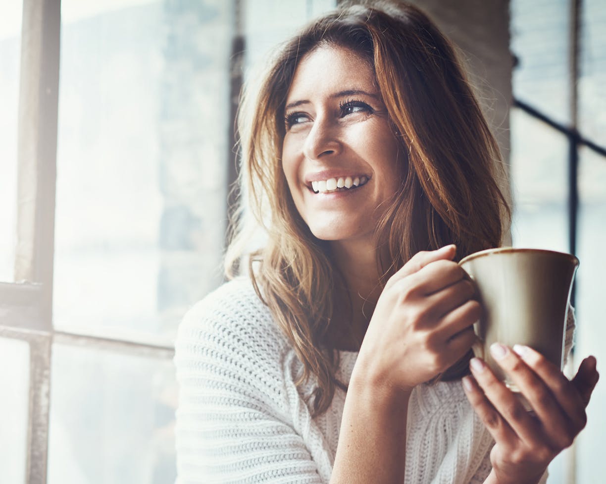 Woman holding a coffe mug smiling