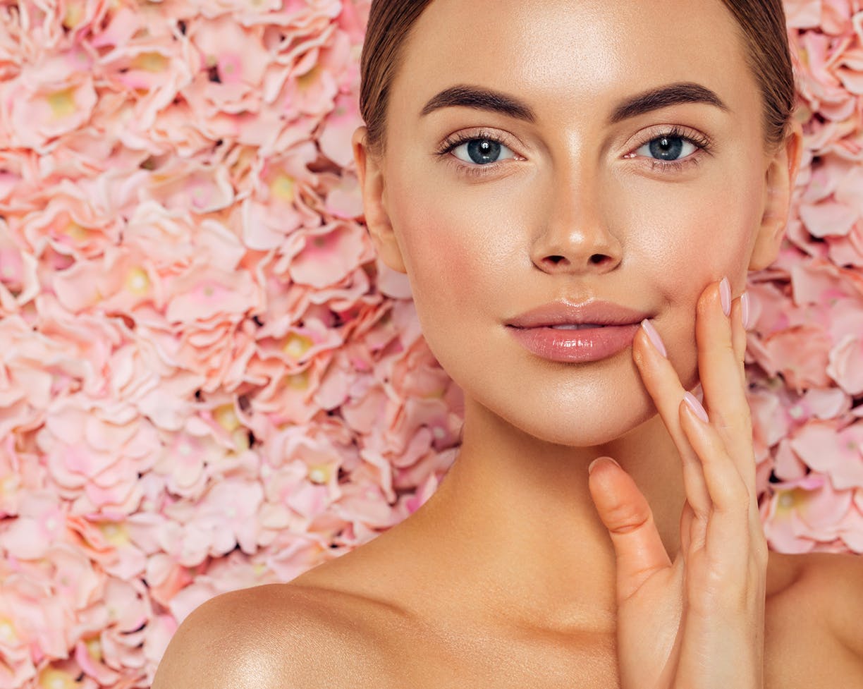 Woman in front of pink flowers touching her mouth